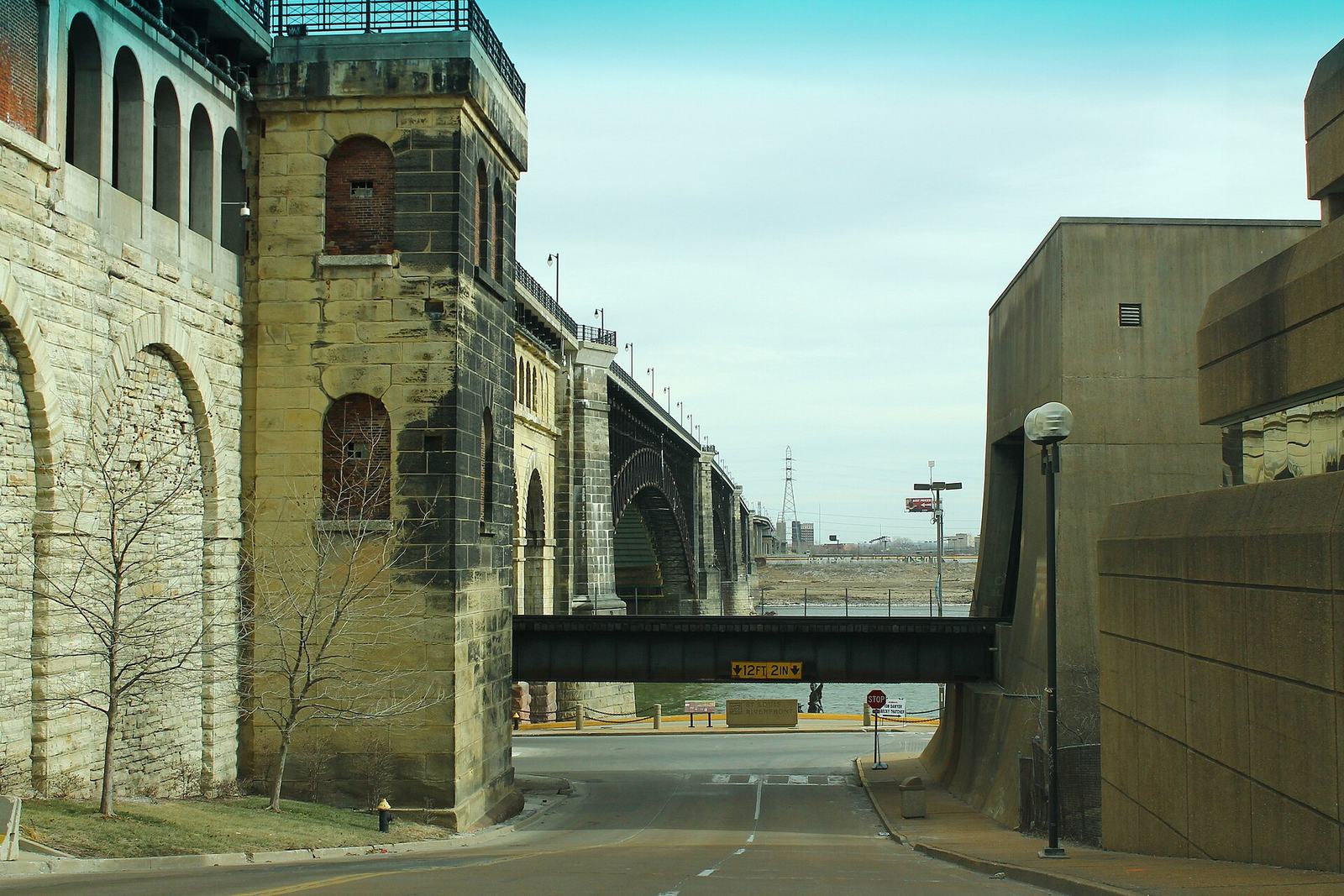 The stone piers and iron spans of the Eads Bridge seen from the St. Louis riverfront street below